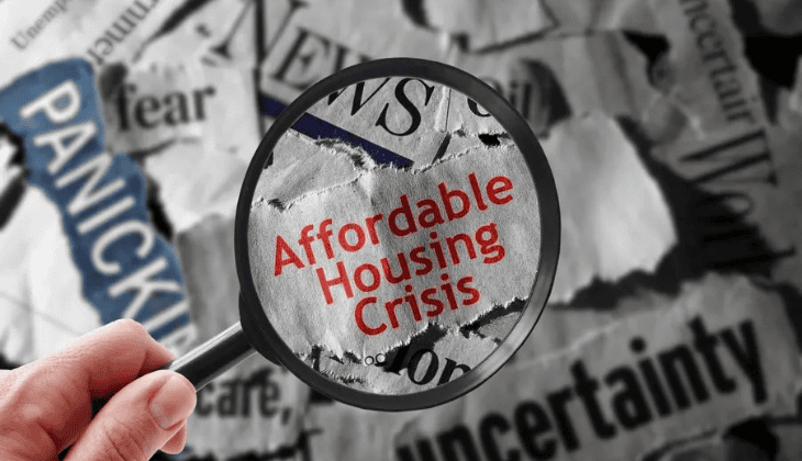Magnifying glass highlighting the words "Affordable Housing Crisis" over torn newspaper headlines.